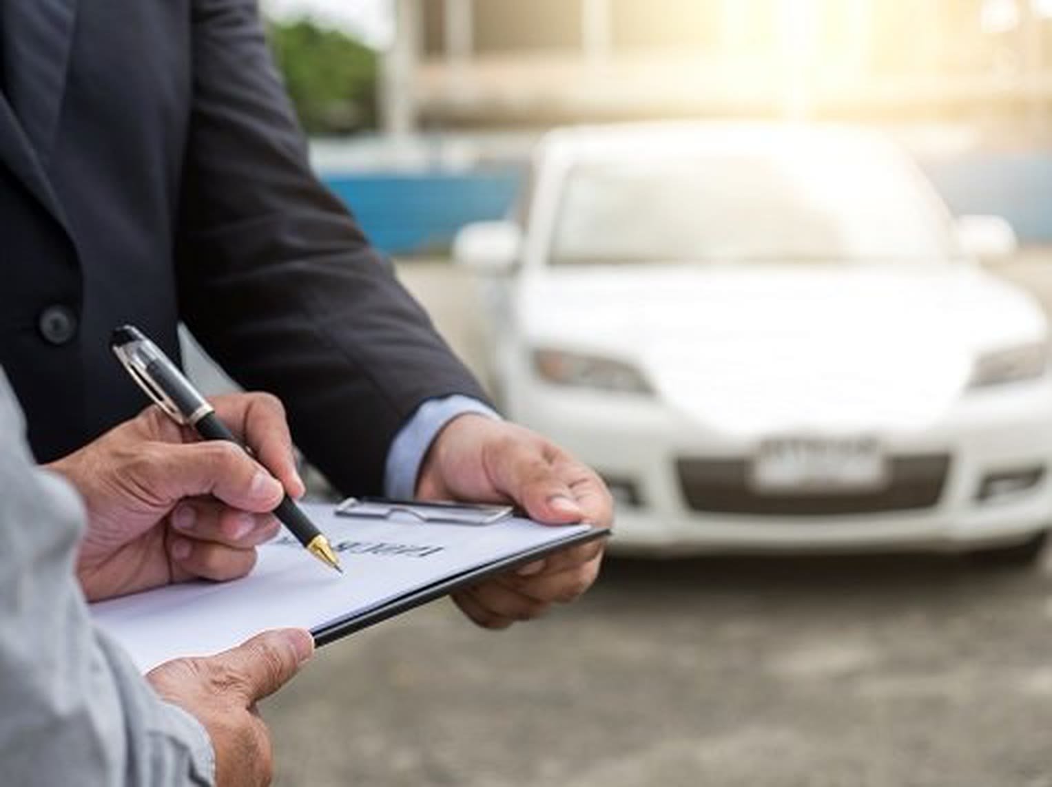 Reviewing insurance claim paperwork beside a customer vehicle