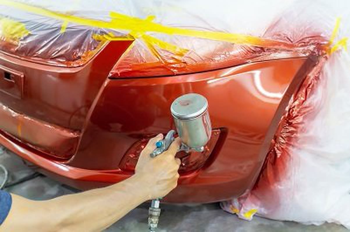 Spray-painting a repaired bumper in the paint booth